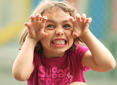 Young girl making cat claws to surprise the photographer