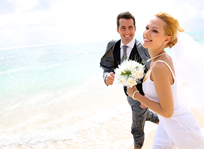 Happy bride and groom walking at he beach